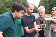 drei Personen sehen auf den Bildschirm der Steuerung einer Drohne 