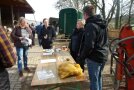 Personen stehen im Halbkreis vor einem Biertisch, auf dem ein Sack Kartoffeln liegt