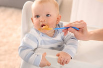 Baby isst Brei von Plastiklöffel 