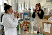 2 Frauen testen Saft in Großküche. 